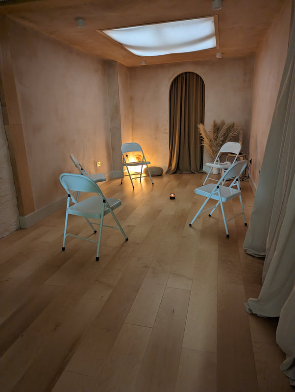 Downstairs space at Native self, soft pink walls, gentle lighting and a circle of plain white chairsPicture